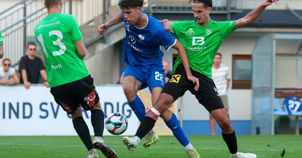 Drei Fußballspieler sind auf einem Feld. Der Spieler in der Mitte trägt ein blaues Trikot mit der Nummer 22. Der Spieler auf der linken Seite trägt ein grünes Trikot mit der Nummer 13. Der Spieler auf der rechten Seite trägt ein grünes Trikot mit der Nummer 27.