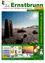 Ein Werbeplakat für die Gemeinde Ernstbrunn, das eine Landschaft mit einer Steinstruktur, einer hellen Sonne und einem klaren blauen Himmel zeigt.