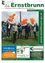 Eine Gruppe von Menschen steht auf einem Feld mit orangefarbenen Luftballons. Sie lächeln und posieren für ein Foto.