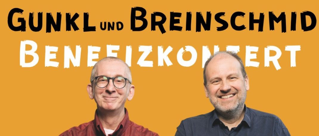 Zwei Männer stehen nebeneinander und lächeln für ein Werbeposter. Einer trägt ein rotes Hemd, der andere ein blaues Hemd. Der Text lautet 'Gunkl und Breinschmid Benefizkonzert'. Unten steht 'Vinzirast' in Weiß auf schwarzem Hintergrund.