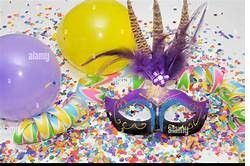 A colorful scene with a purple mask, yellow and purple balloons, and confetti on a white background. The mask is decorated with purple feathers.