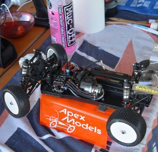 Ein ferngesteuertes Apex Models Auto auf einem Tisch mit Werkzeugen und einer Flasche Fahrradreiniger.