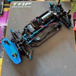 Ein Bild des Tamiya Racing Factory Modellauto-Chassis liegt auf einer Arbeitsfläche mit grauer Oberfläche.