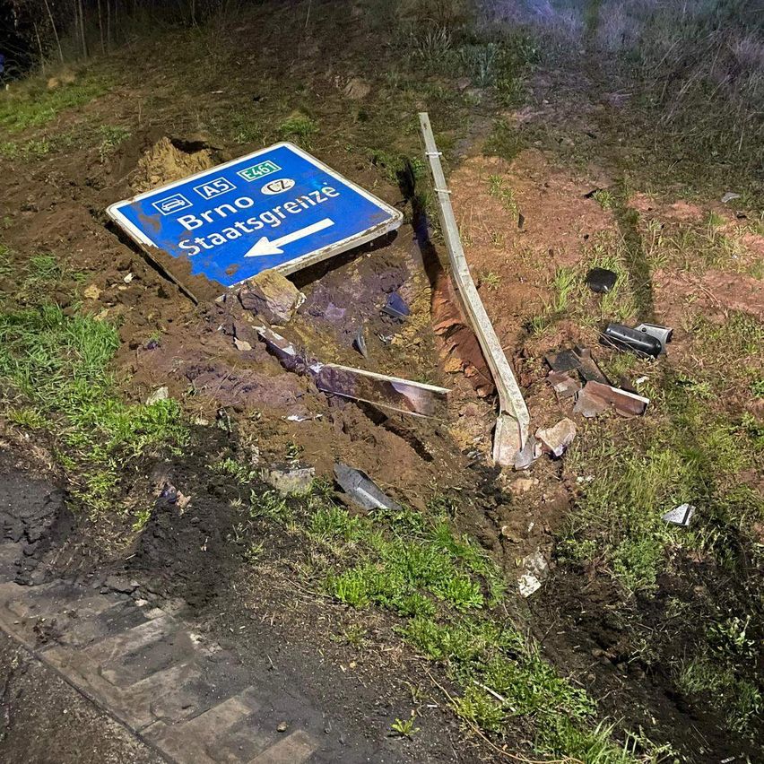 Ein blaues Straßenschild für die Staatsgrenze von Brno und ein Metallpfahl sind an der Straßenseite zerbrochen.