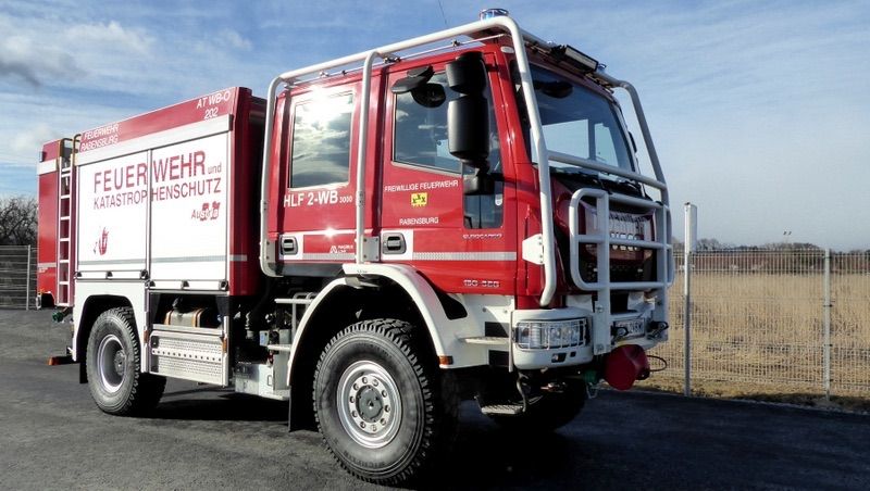Ein roter Feuerwehrwagen mit einer Leiter an der Seite steht am Straßenrand.