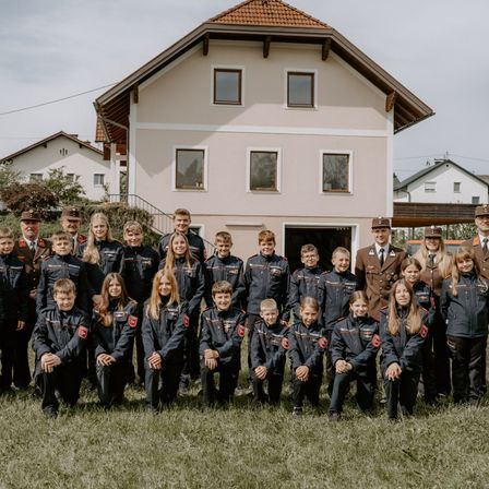 Eine Gruppe uniformierter Kinder und Erwachsener posiert für ein Foto vor einem Haus.