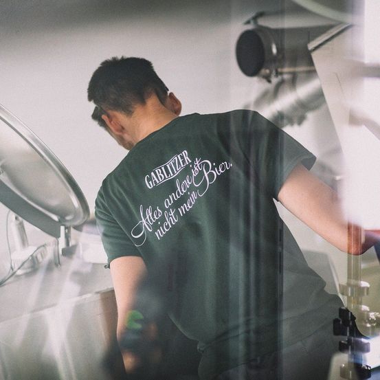 Bild enthält, Person, Clothing, T-Shirt, Cleaning, Architecture, Building, Factory, Head