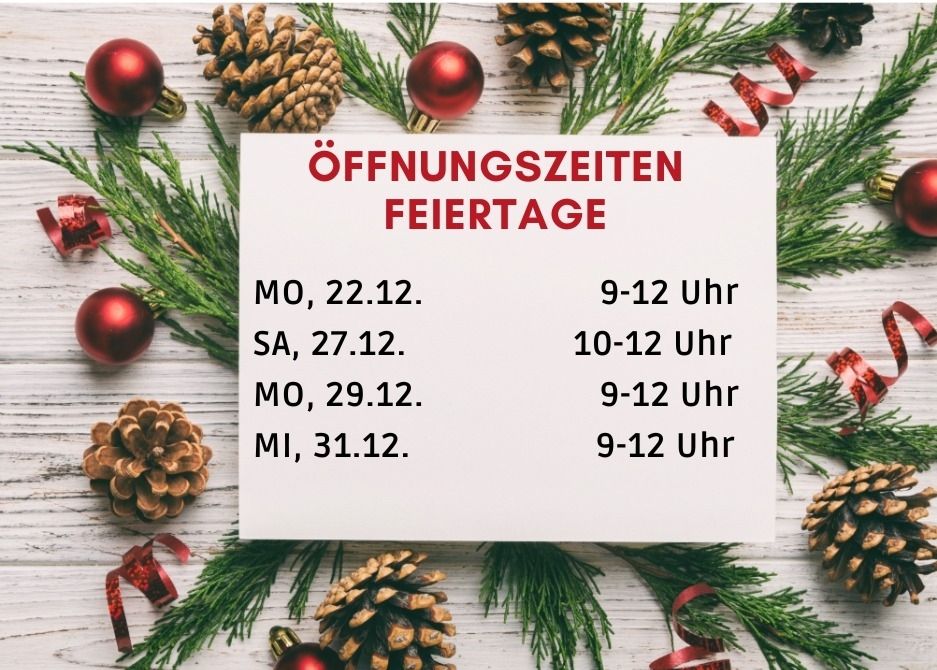 Eine weiße Karte mit rotem Text zeigt auf einer Holzoberfläche mit Weihnachtsdekoration die Öffnungszeiten an Feiertagen. Zeigt Daten und Zeiten für vier bestimmte Tage an.