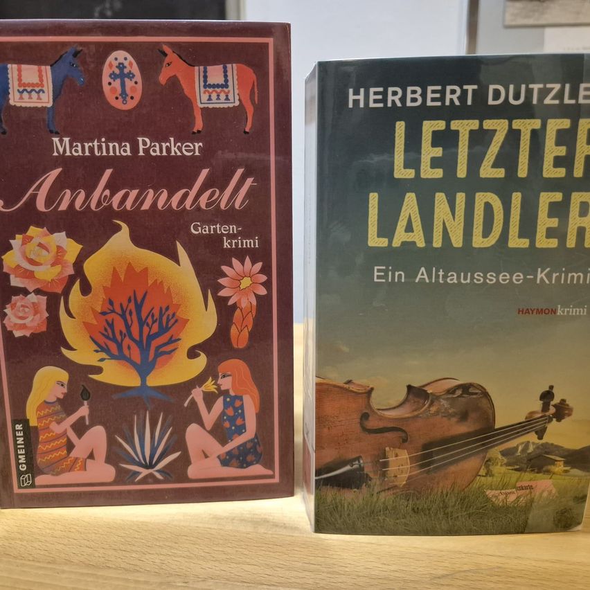 Two books are displayed side by side on a wooden table. One book is titled 'Anbandelt' by Martina Parker, and the other is titled 'Letzter Landler' by Herbert Dutzle.