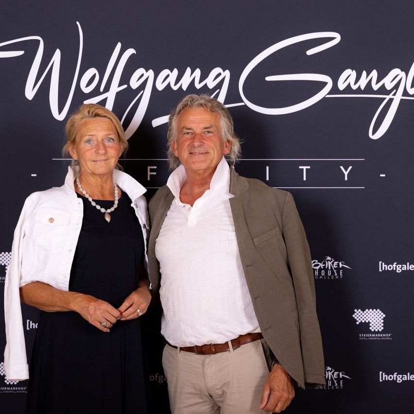 Ein Mann und eine Frau stehen nebeneinander vor einem Wolfgang Gangl Eventbanner.