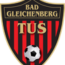 Das Logo der Bad Gleichenberg Fußballmannschaft zeigt einen schwarzen Schild mit goldenem Rand, einem rot-schwarz gestreiften Hintergrund und einem Fußball in der Mitte.