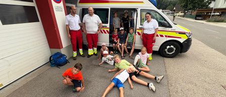 Mehrere Erwachsene und Kinder posieren vor einem Krankenwagen. Ein Erwachsener steht in der Tür des Krankenwagens.