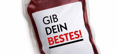 Ein durchsichtiger Beutel enthält rote Flüssigkeit, wahrscheinlich Blut, mit den Worten 'Gib Dein Bestes!' in Fettschrift auf einem weißen Etikett.