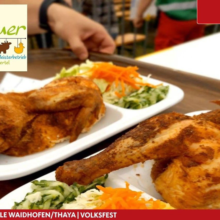 Zwei Teller mit gebratenem Hühnchen und Gemüse mit einem verschwommenen Hintergrund einer Person und einem roten Logo.