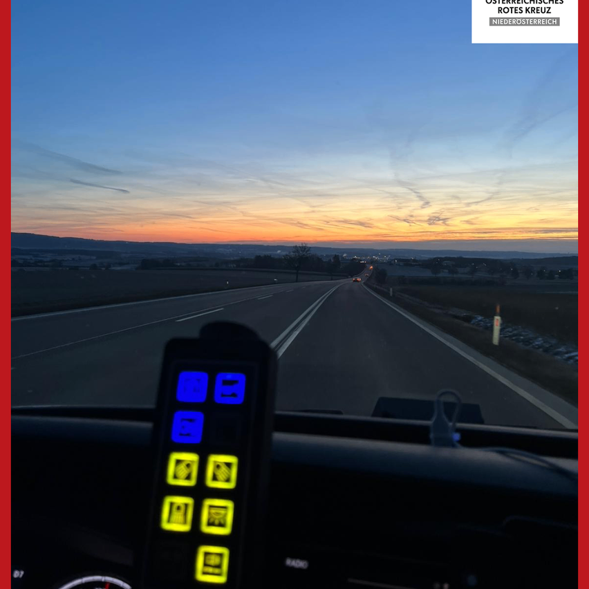 Ein Blick auf das Armaturenbrett eines Autos, das eine Autobahn mit Sonnenuntergang zeigt, mit beleuchteten Tasten auf der linken und einem Radio auf der rechten Seite.
