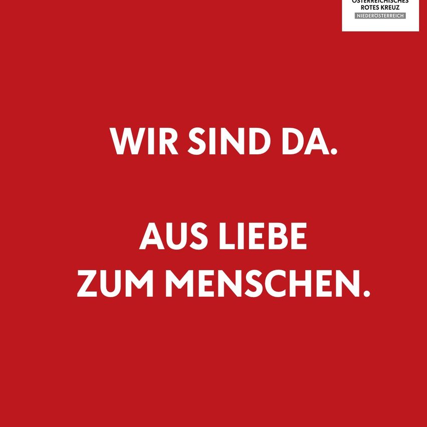 A red background displays white text. The top line reads 'WIR SIND DA.' The bottom line reads 'AUS LIEBE ZUM MENSCHEN.' The red cross logo is at the top right corner.