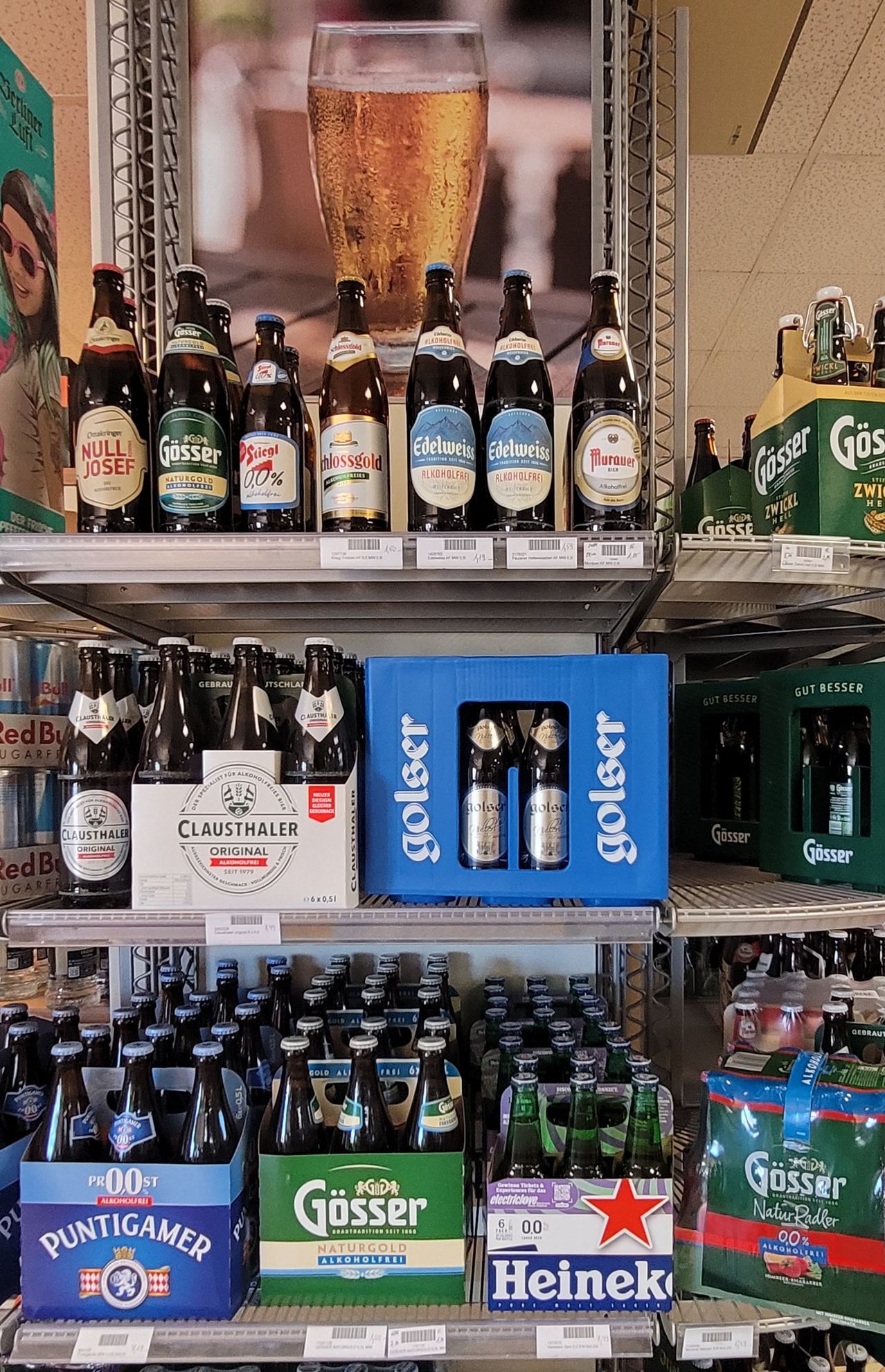 Ein Ladenregal voller verschiedener Bierflaschen, darunter Clausthaler, Edelweiss und Murauer. Flaschen sind ordentlich angeordnet, wobei Clausthaler Original prominent präsentiert wird.