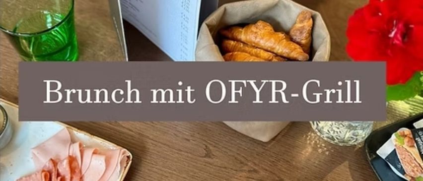Ein Holztisch zeigt ein Teller mit geschnittenem Fleisch, einem Messer, einer Gabel und einem Blumenvase. Ein Menükarte, ein Glasbecher und ein Korb mit Brot sind ebenfalls vorhanden. Die Worte 'Brunch mit OFYR-Grill' sind auf dem Bild geschrieben.