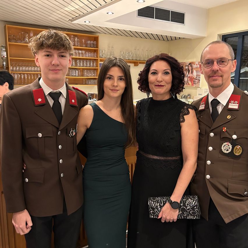 Drei Personen in Militäruniformen stehen eng beieinander und lächeln für ein Foto. Zwei Männer und eine Frau, alle in formeller Kleidung.