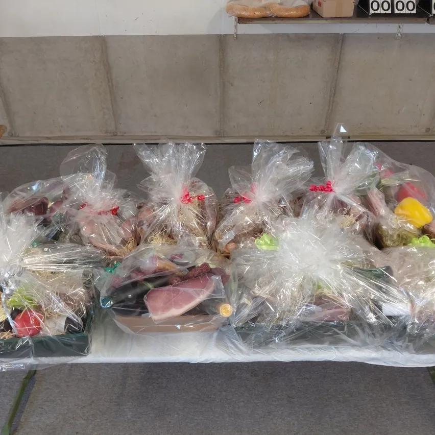 Ein Tisch mit mehreren Plastiktüten, gefüllt mit verschiedenen Lebensmitteln wie Fleisch, Gemüse und Brot, in einer Reihe angeordnet.