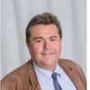Ein lächelnder Mann in einer braunen Jacke und blauer Krawatte ist abgebildet über dem Namen Mag. Michael Ableidinger. Darunter ist eine Telefonnummer.