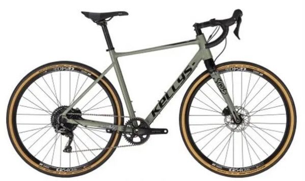 Ein grünes Mountainbike mit schwarzen Lenker und Sitz, gebrandet mit 'KELLYS' auf dem Rahmen. Das Fahrrad hat schwarze Reifen mit braunen Felgen.