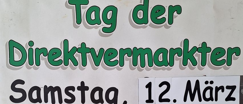 Ein weißer Schilderkasten mit den Worten 'Direktvermarkter' in Grün und 'Samstag, 12. März' in Schwarz. Darunter sind Bilder von Lebensmitteln, darunter Würste, Brot, Käse, Wein und Obst.