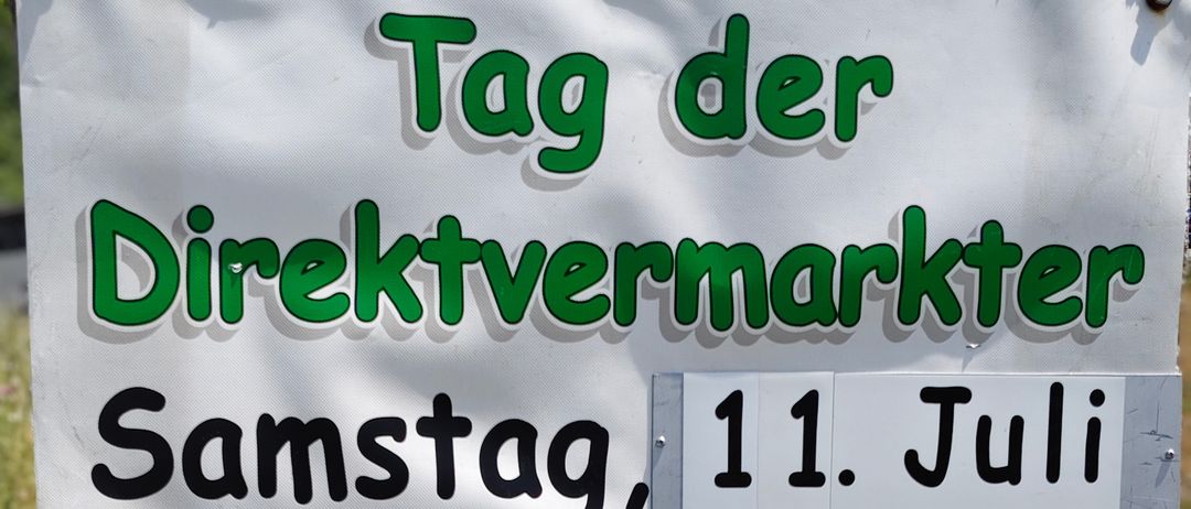 Ein Schild für Direktvermarkter mit Produkten wie Fleisch, Würsten, Marmeladen, Wein und Blumen. Der Markt findet am Samstag, 11. Juli, von 9 Uhr bis 13 Uhr von Fam. MENITZ in Eisenstädterstr. 18, 2485 Wimpassing statt.