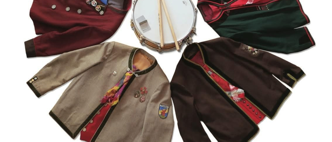 Plakat für eine traditionelle Veranstaltung am 3. Mai 2025 um 20:00 Uhr in Kotschach-Mauthen. Das Plakat zeigt verschiedene Kostüme und eine Trommel, mit Texten zu Ticketpreisen und Beginn der Veranstaltung.