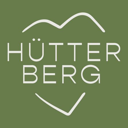 Das Logo für Hutterberg auf grünem Hintergrund, mit einem stilisierten Berg und einem Herz mit lächelndem Gesicht.