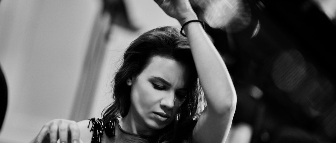 Ein Schwarz-Weiß-Foto zeigt eine Frau beim Tanzen, ihr Haar weht im Wind, die Augen geschlossen, ein Arm erhoben, die andere Hand am Kopf.