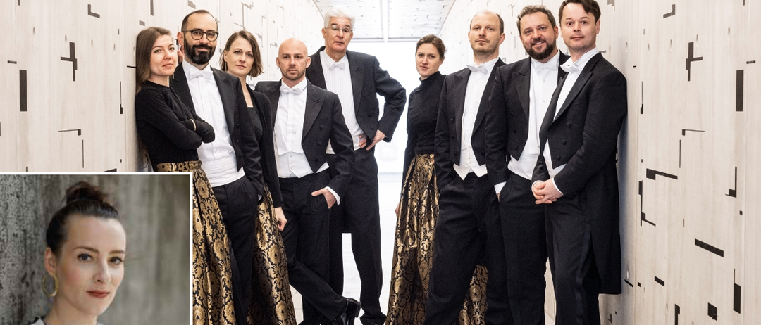 Eine Gruppe formell gekleideter Personen, möglicherweise Musiker, steht in einer Reihe und sieht die Kamera an. Sie tragen schwarze Anzüge und Fliegen, wobei die Frauen in der Gruppe elegante Kleider tragen.