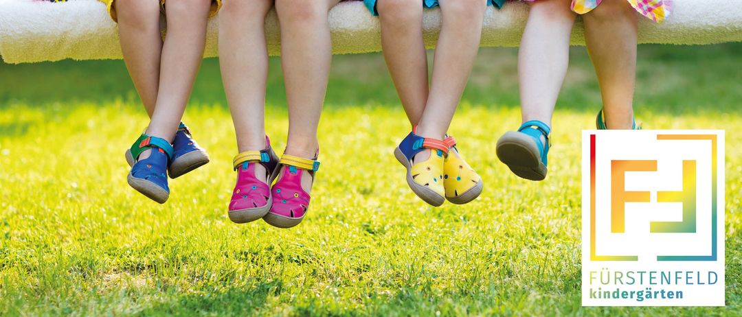 Vier Kinder sitzen auf einer Bank und tragen passende Sandalen. Sie tragen leuchtende Farben und Freizeitkleidung, die sich für Aktivitäten im Freien eignet.