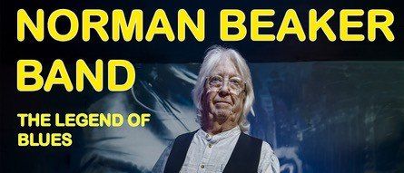 Ein Mann mit einer Gitarre steht auf der Bühne. Über ihm steht Norman Beaker Band, die Legende des Blues. Ein Foto eines Mannes ist hinter ihm.
