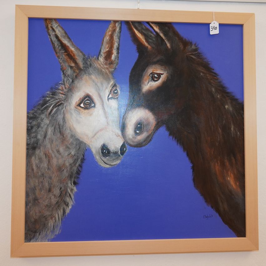 Ein gerahmtes Gemälde von zwei Eseln, die sich auf einem blauen Hintergrund gegenüberstehen.