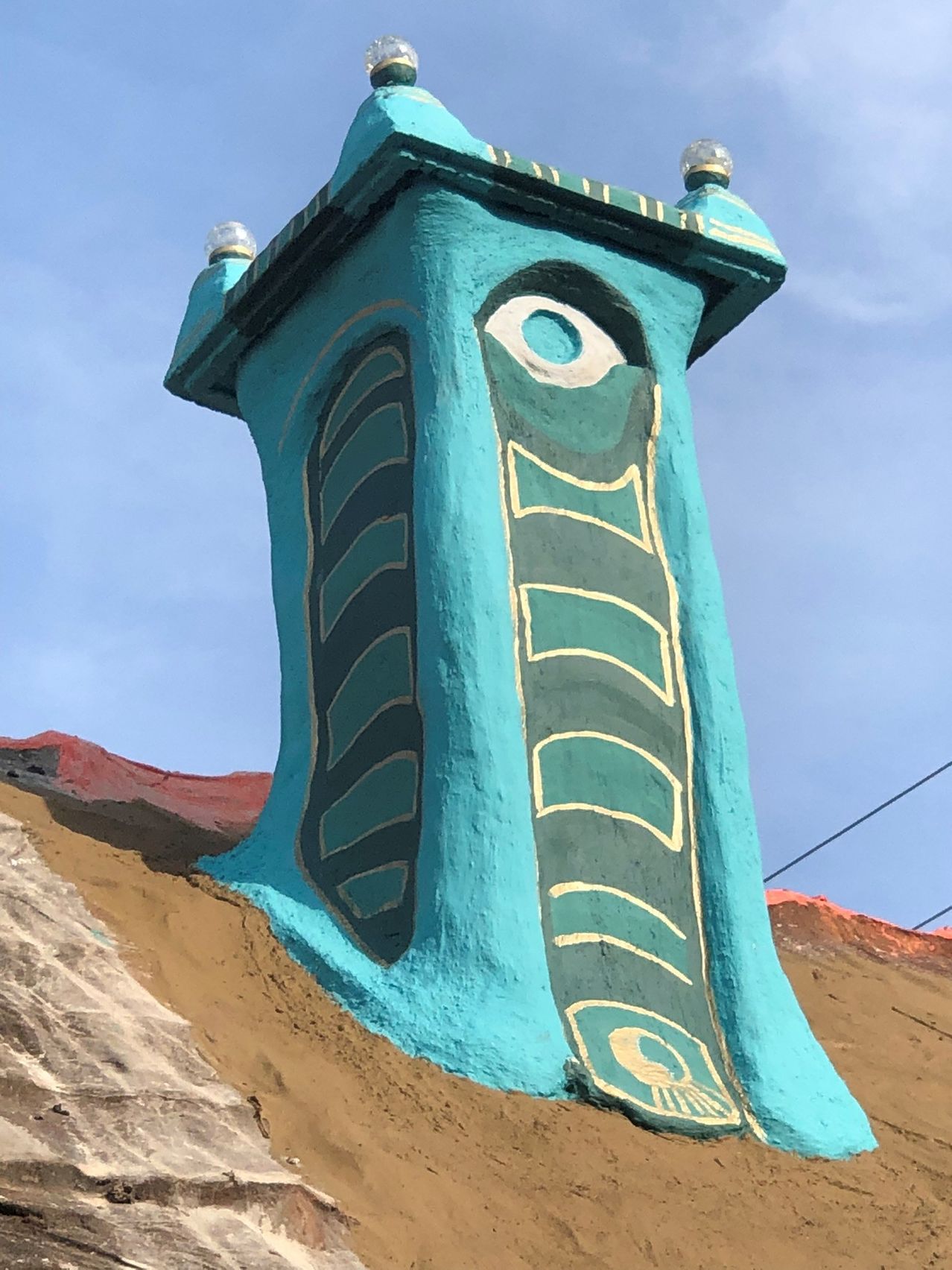 Ein Nahaufnahme einer blauen Schornstein mit einem Fischdesign, das darauf gemalt ist, unter einem blauen Himmel.