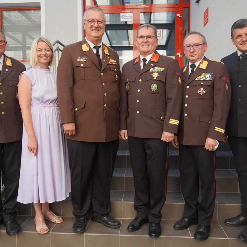 Fünf Personen in Militäruniformen und eine Frau in einem weißen Kleid stehen auf einer Treppe. Sie scheinen alle für ein Foto zu posieren.
