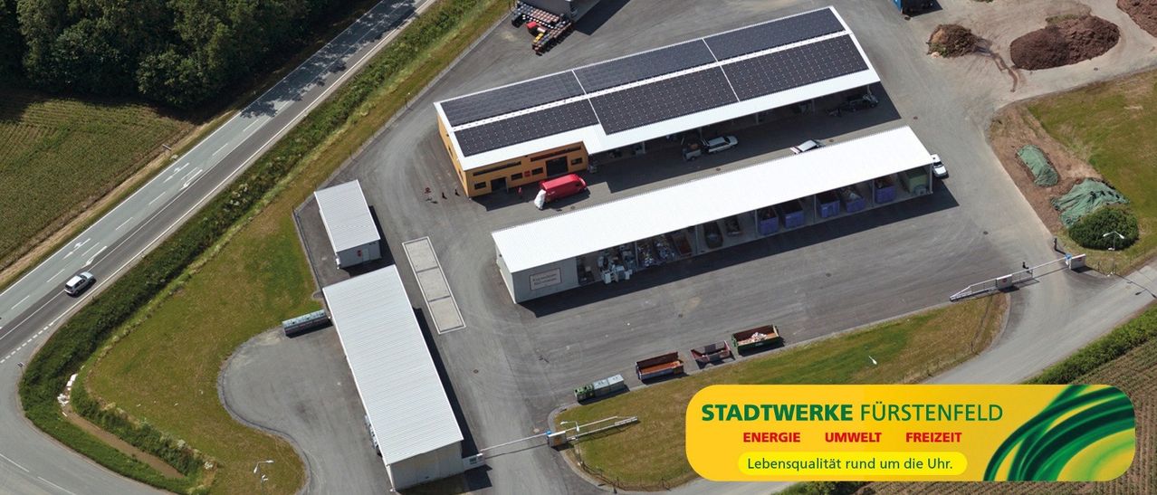 Luftaufnahme einer Anlage mit Solarpanelen auf dem Dach und mehreren Gebäuden, mit Fokus auf Energie und Lebensqualität.