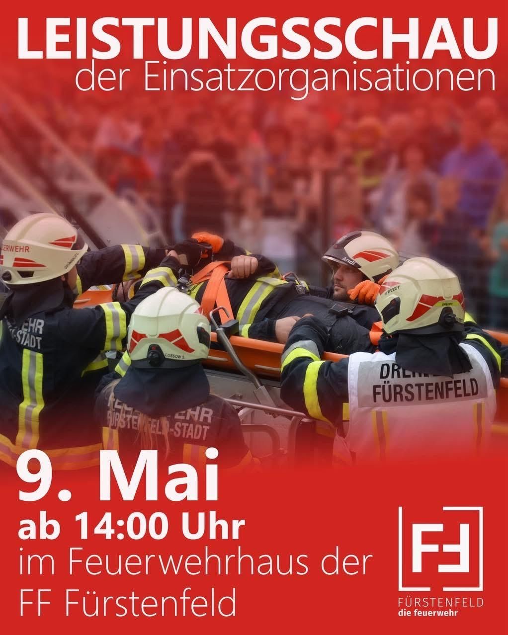 Feuerwehrleute in Schutzkleidung helfen einem Patienten auf einer Trage, mit einer Menge im Hintergrund. Datum und Uhrzeit werden als 9. Mai um 14:00 Uhr angezeigt.