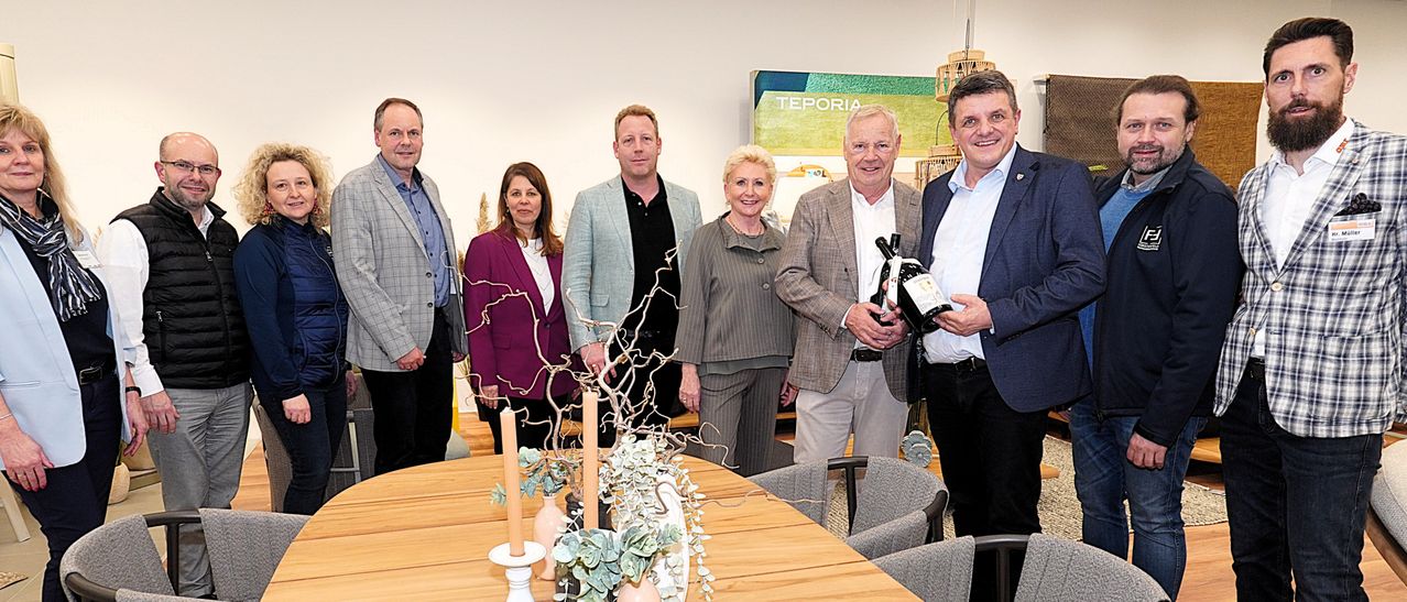 A group of people dressed in formal wear are posing for a photo with a table centerpiece in front of them.