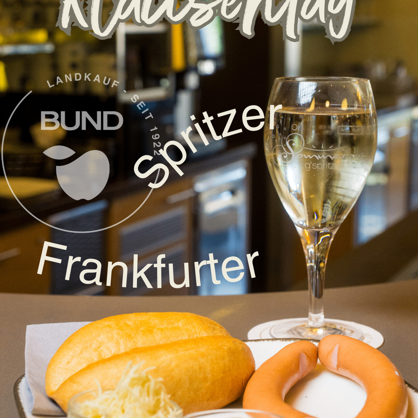 Ein Glas Weißwein, eine Wurst und Brot mit Käse stehen auf einem Tisch. Das Bild hat verschwommenen Text, der 'Frankfurter Spritzer' und 'Landkauf Bund Seit 1922' lautet.