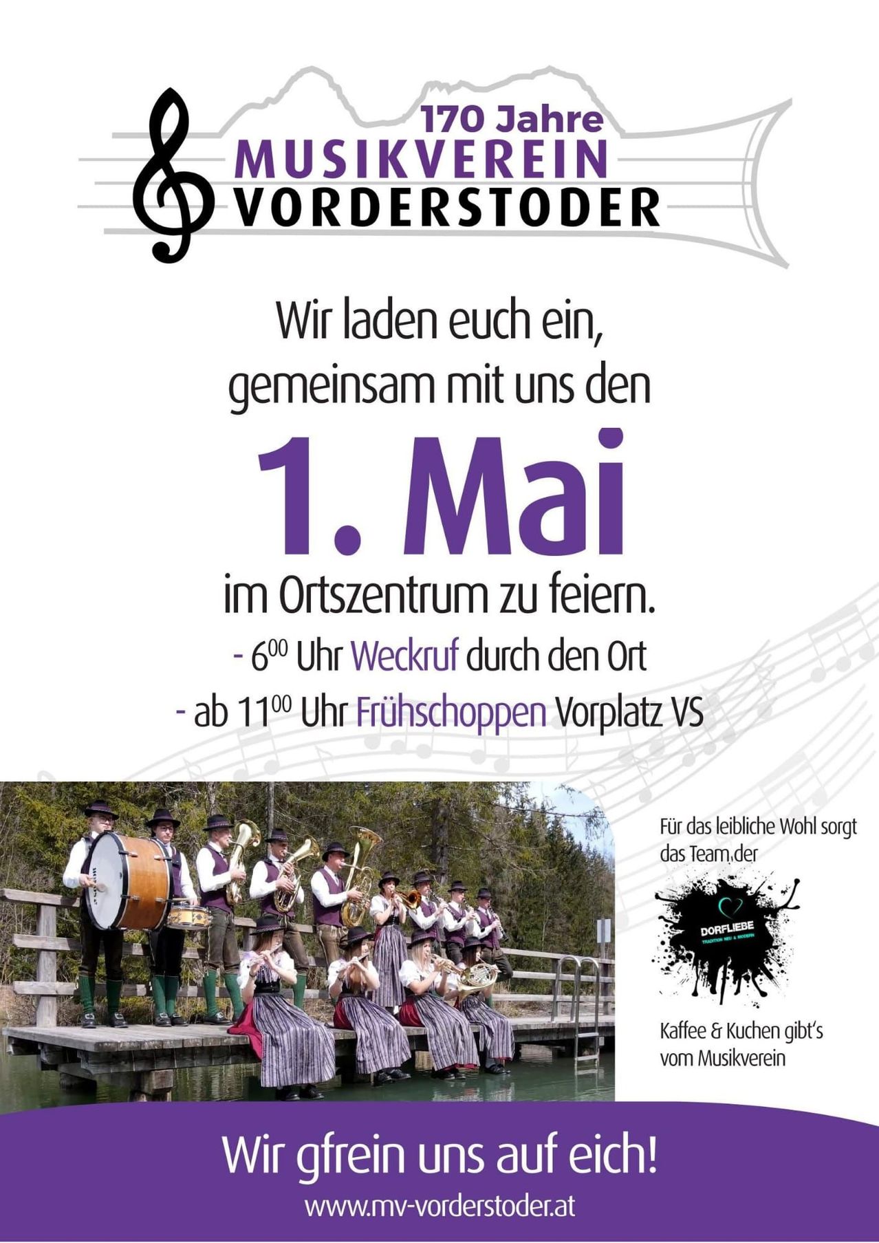 Eine Anzeige lädt ein, am 1. Mai im Ortszentrum zu feiern. Veranstaltungen beinhalten ein Weckruf um 6 Uhr durch den Ort und ein Frühstück auf dem Dorfplatz. Unten steht eine Gruppe von Musikern in traditioneller Kleidung beim Spielen.