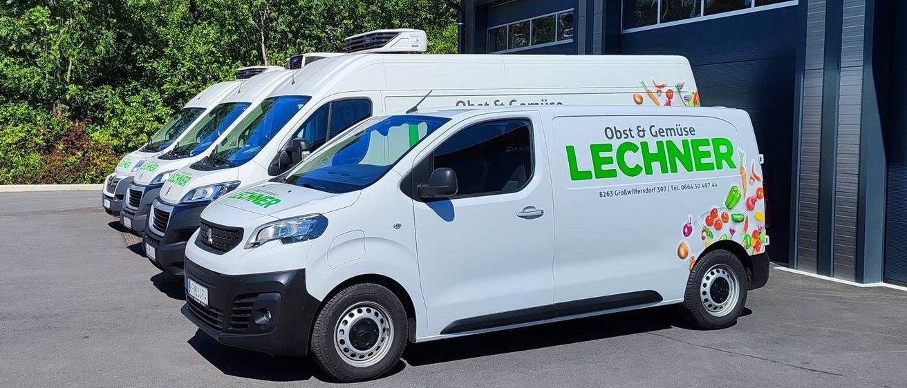 Drei weiße Lieferwagen sind vor einem Gebäude mit blauem Dach geparkt. Die Lieferwagen haben das Wort 'LECHNER' auf der Seite geschrieben.