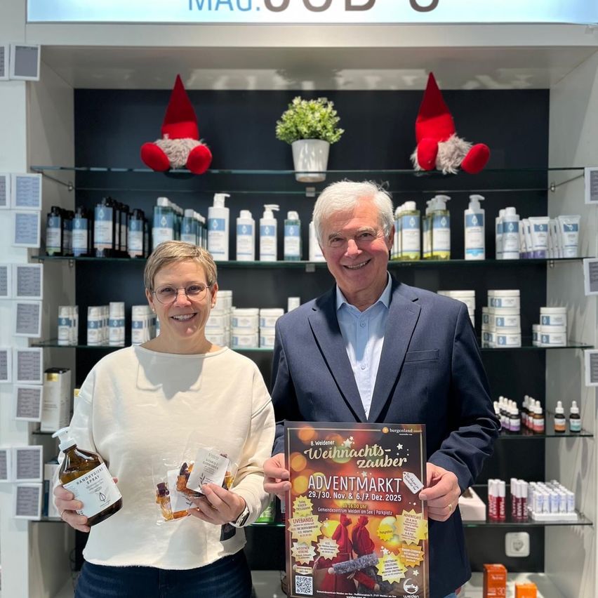 Zwei Personen stehen in einem Geschäft und halten Produkte und einen Kalender. Das Geschäft hat Regale mit verschiedenen Produkten und Weihnachtsdekorationen.