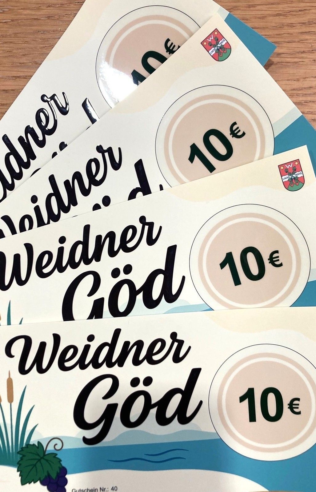 Stapel von Weidner God-Gutscheinen, jeder mit einem Wert von 10 Euro, auf einer Holzoberfläche präsentiert. Die Gutscheine sind weiß mit schwarzer Schrift und einem beigen Kreis.