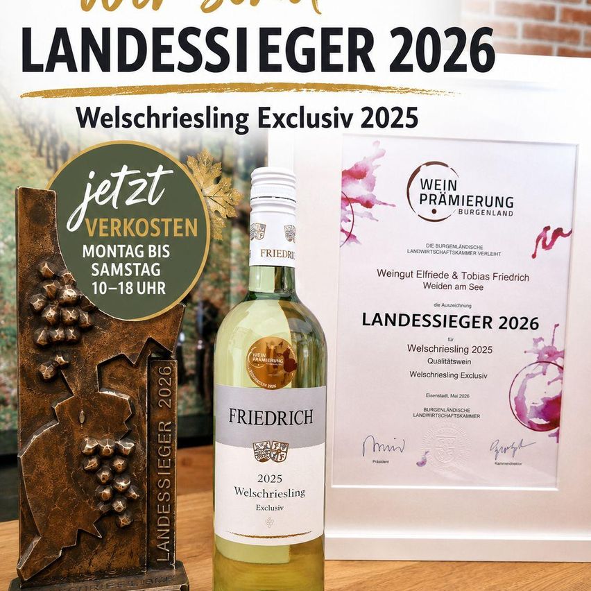 Eine Flasche Friedrich 2025 Welschriesling Exklusiv Wein wird zusammen mit einem Bronzepokal und einem Zertifikat auf einem Holztisch ausgestellt. Der Pokal zeigt den Text "Landessieger 2026".
