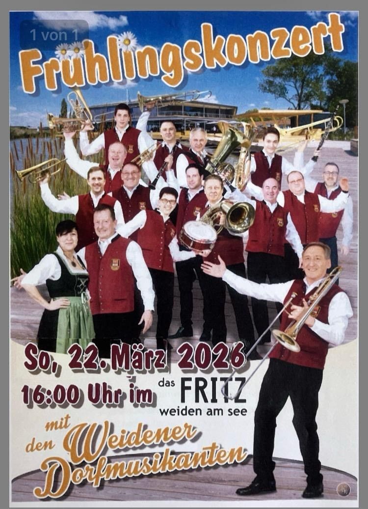 Eine Gruppe von Musikern in roten Westen, die Blechblasinstrumente halten, posiert für ein Foto mit einer Frau in traditioneller deutscher Kleidung. Das Datum 22. März 2026 und die Zeit 16:00 Uhr sind angezeigt.