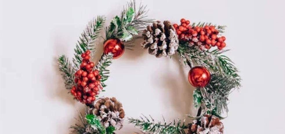 Eine Weihnachtsgirlande mit roten Beeren und Tannenzapfen, gehalten von zwei Händen vor weißem Hintergrund. Der Text 'KINDERGARTEN JAKLING' steht oben.