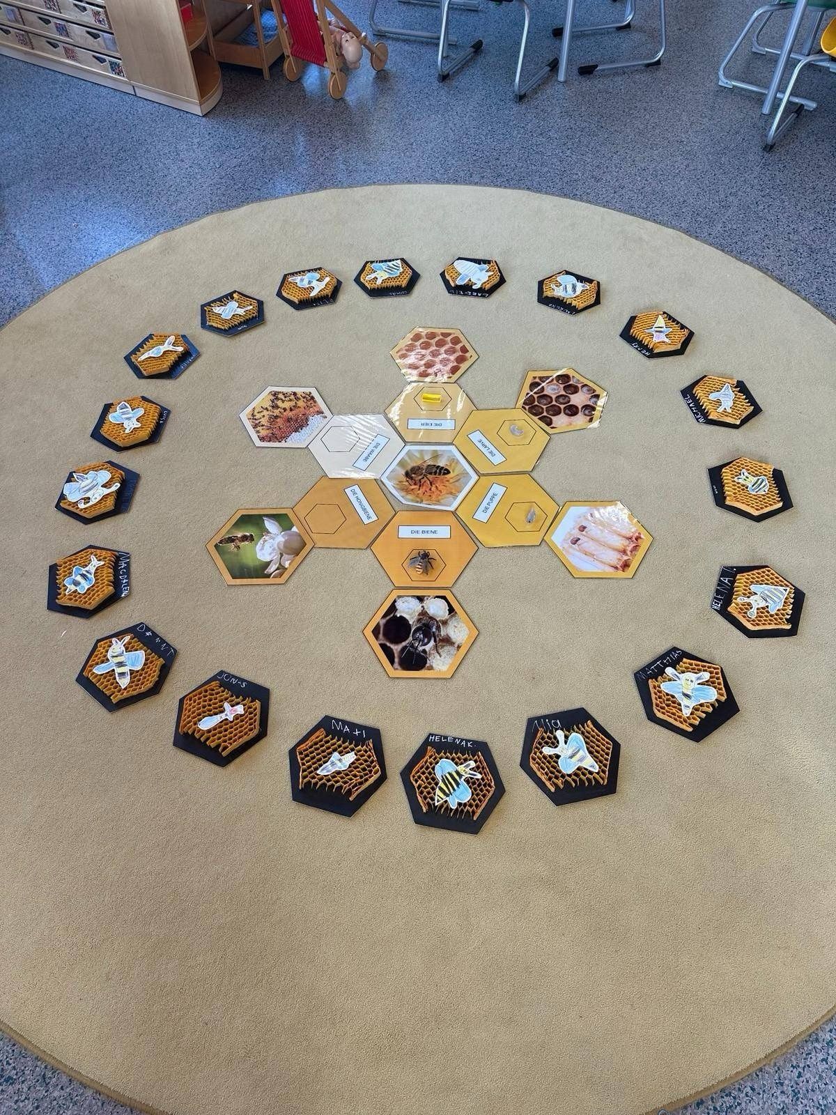 Eine kreisförmige Anordnung von sechseckigen Kacheln mit bienenbezogenen Bildern, auf einem beigen Teppich platziert, zeigt verschiedene Designs, darunter Honigwaben und Bienen.