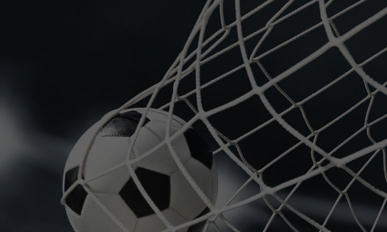 Ein Fußball ist in einem Netz gefangen, das seine schwarzen und weißen Muster zeigt. Das Netz ist straff gespannt und betont die runde Form des Balls.